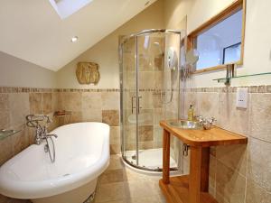 ein Badezimmer mit Badewanne, Waschbecken und Dusche in der Unterkunft Cae'r Dyni Caer Dyni in Criccieth