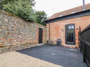 a brick building with a table next to a door at Grange Barn in Hessett