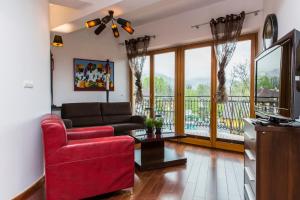 sala de estar con sofá rojo y balcón en TatryTop Gorące Źródła Spa en Zakopane