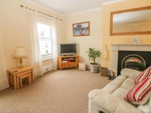 uma sala de estar com um sofá e uma televisão em Saltwood em Eastbourne