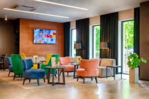 Focus Hotel Premium Lublin في لوبلين: غرفة انتظار مع كراسي وطاولات ملونة