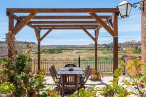 a wooden pergola with a table and chairs on a patio at Villayana Holiday Home in San Lawrenz