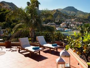 a patio with two chairs and a palm tree at Hotel Sirius in Taormina