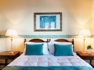 a bedroom with a bed with blue pillows and two lamps at Hotel Sirius in Taormina