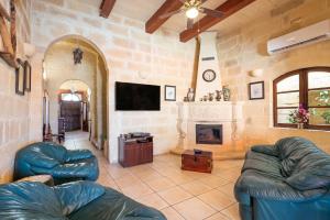a living room with two leather couches and a fireplace at Villayana Holiday Home in San Lawrenz