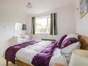 a bedroom with a bed with a purple blanket at Brambles in Gorran Haven