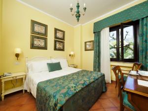 a bedroom with a bed and a desk and a window at Hotel Sirius in Taormina