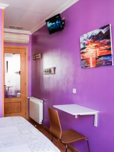 Dormitorio con pared morada, cama y escritorio en RC Miguel Angel, en Madrid