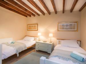 two twin beds in a room with wooden ceilings at The Coach House - Beaumaris in Beaumaris