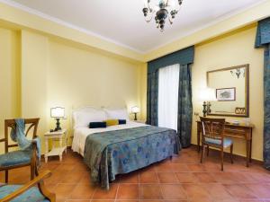 a bedroom with a bed and a desk and chairs at Hotel Sirius in Taormina