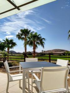 a white table and chairs on a patio with palm trees at Mundo Aguilon 1 Chambre 4100 in San Juan de los Terreros