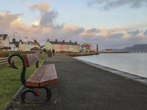 a park bench sitting next to a body of water at The Coach House - Beaumaris in Beaumaris