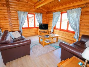 una sala de estar con sofás y TV en una cabaña de madera en Yew Lodge, en Oakham