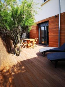 une terrasse en bois avec une table et un arbre dans l'établissement L'horizon - Bord de mer, à Ploemeur