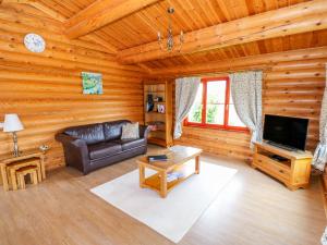 a living room with a couch and a tv in a log cabin at Cedar Lodge in Oakham
