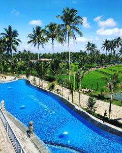 a swimming pool at a resort with palm trees at Grand Harvest Resort & Villas in Banyuwangi