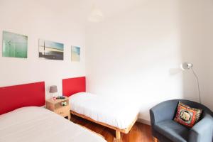a bedroom with a bed, chair, desk and a lamp at Inn Possible Lisbon Hostel in Lisbon
