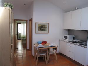 eine Küche mit einem Tisch und eine kleine Küche mit weißen Schränken in der Unterkunft Casa do Cais Cerveira in Vila Nova de Cerveira