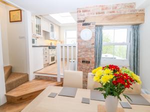 a kitchen and dining room with a table and flowers at Wyebrow Cottage in Bakewell
