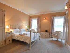 a bedroom with a bed and a chair and windows at Dinas Noddfa in Beddgelert