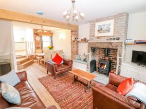 a living room with leather furniture and a fireplace at Wyebrow Cottage in Bakewell