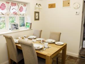 a dining room table with chairs and a wooden table with plates at Wash House Cottage in Much Wenlock