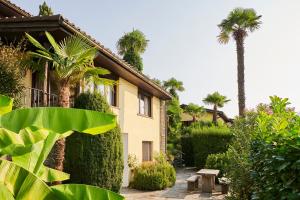 a house with palm trees and plants in front of it at Reka-Ferienanlage Brissago in Brissago