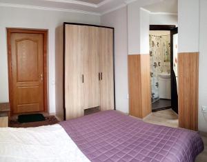 - une chambre avec un lit violet et une armoire en bois dans l'établissement Сонячна, à Trouskavets