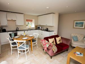 a kitchen and a living room with a table and a couch at Estuary Cottage in Penrhos-Lligwy