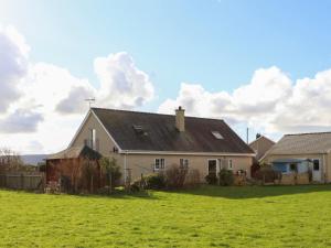una casa con un campo verde delante de ella en Dwyros, en Pwllheli
