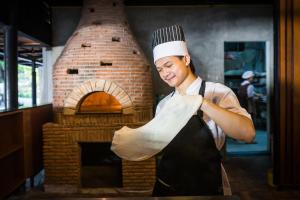 a man in an oven holding a piece of bread at Cocohut Beach Resort Koh Phangan in Haad Rin +37 photos