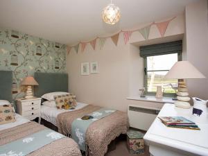 a small bedroom with two beds and a desk at Estuary Cottage in Penrhos-Lligwy