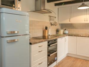 a kitchen with white cabinets and a refrigerator at The Cottage, Polwarth Crofts in Duns