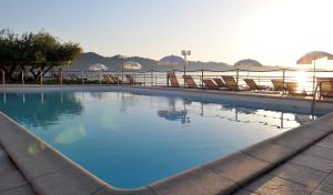 uma grande piscina com cadeiras e o oceano em Hotel Tettola em Saint-Florent