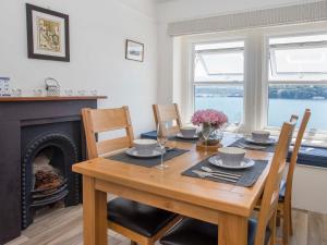 a dining room with a table and a fireplace at Glan Dwr Bach in Llandegfan