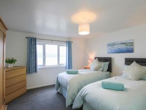 a bedroom with two beds and a window at Glan Dwr Bach in Llandegfan