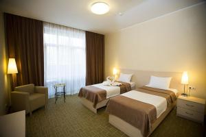 a hotel room with two beds and a chair at Crona Hotel and SPA in Berdsk