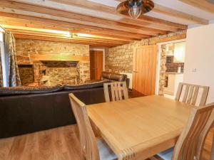 une salle à manger avec une table en bois et une cheminée dans l'établissement Crooked Hill Cottage, à Ammanford