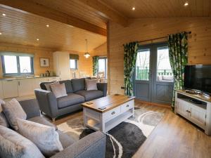 a living room with two couches and a tv at Oak Lodge in Ulverston
