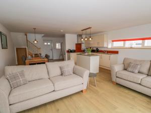 a living room with two couches and a kitchen at Coney Garth Cottage in Beckermet