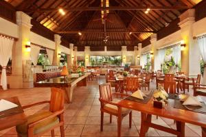 un restaurante con mesas de madera y sillas de madera en Bali Mandira Beach Resort & Spa, en Legian