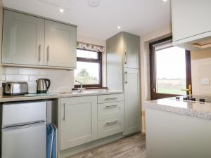 a kitchen with white cabinets and a window at Little May in Newquay +4 photos
