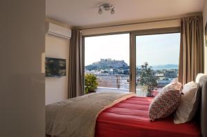 a bedroom with a red bed with a large window at Acropolis View Rooftop Apartment Athens in Athens