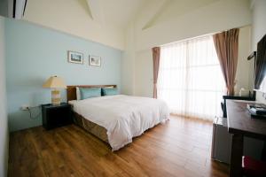 a bedroom with a white bed and a wooden floor at He Sen B&B in Kenting