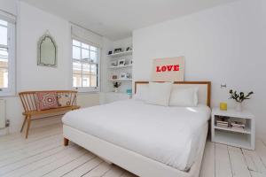 a white bedroom with a large white bed with a love sign on it at Veeve - Princedale Road Minimalism in London