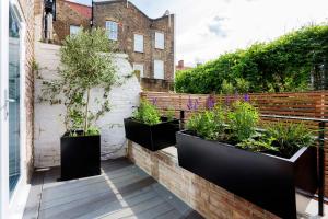 a row of plants in black pots on a balcony at Veeve - Princedale Road Minimalism in London