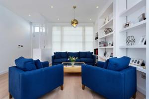 a living room with blue couches and a table at Veeve - Princedale Road Minimalism in London