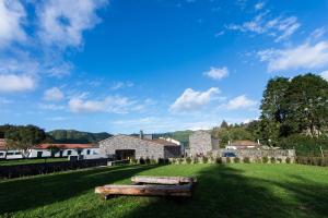 a grassy field with a stone building and a bench at Sete Cidades Quinta Da Queiró in Sete Cidades