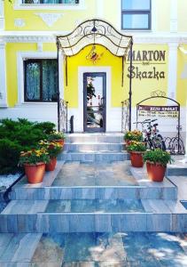 un edificio amarillo con escaleras y flores en ollas en Marton Skazka Hotel, en Rostov-on-Don