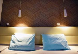 a bed with two pillows and a wooden head board at Hai Hotel in Larnaca